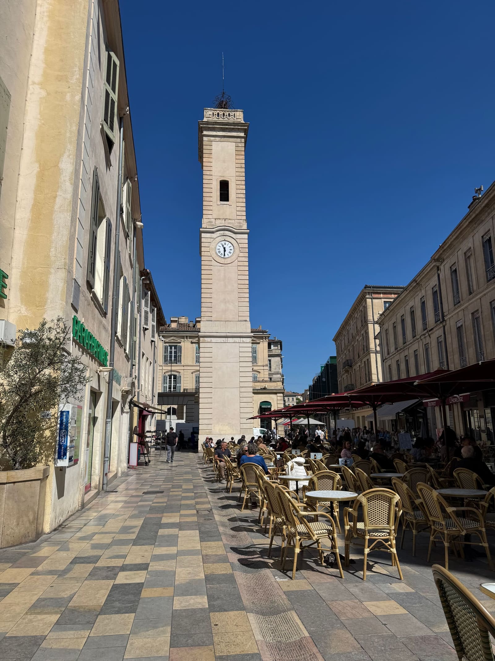 la Tour de l'Horloge in fondo alla via, con i tavolini dei caffè al sole