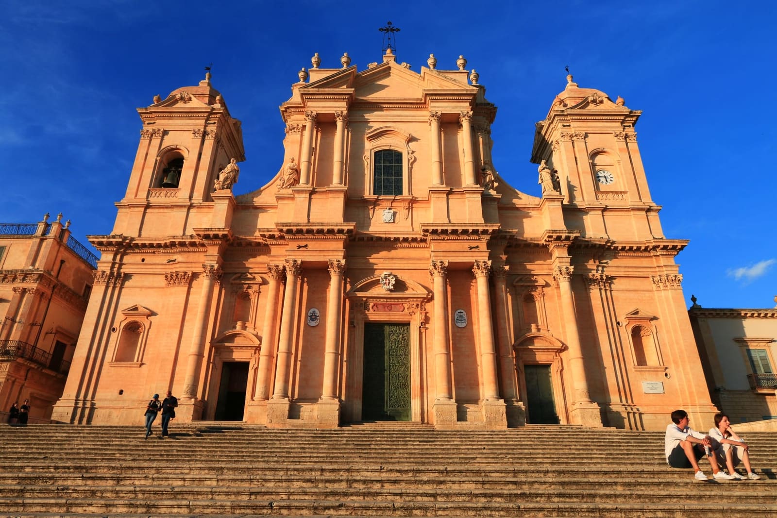la facciata della cattedrale accesa dal sole basso, con le due torri campanarie