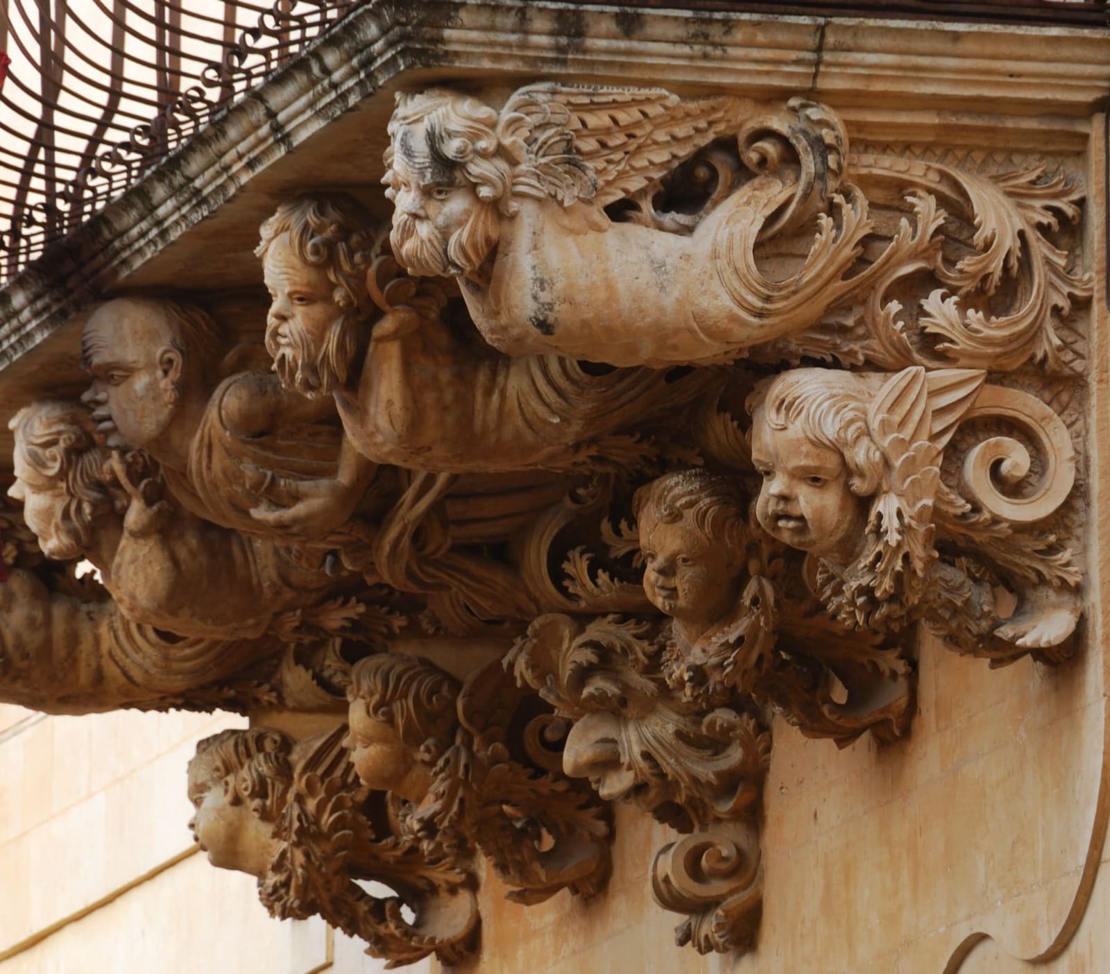 da vicino, i putti e i mostri scolpiti nella mensola di un balcone di Palazzo Nicolaci