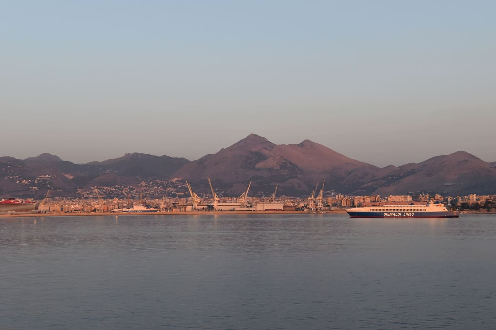 Palermo vista dal mare all'alba, con il porto e i monti della Conca d'oro dietro