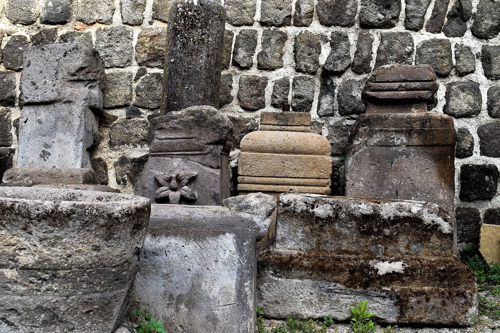 il cortile interno del castello, con le urne, i cippi e i pezzi di pietra scolpita appoggiati al muro di pietra scura
