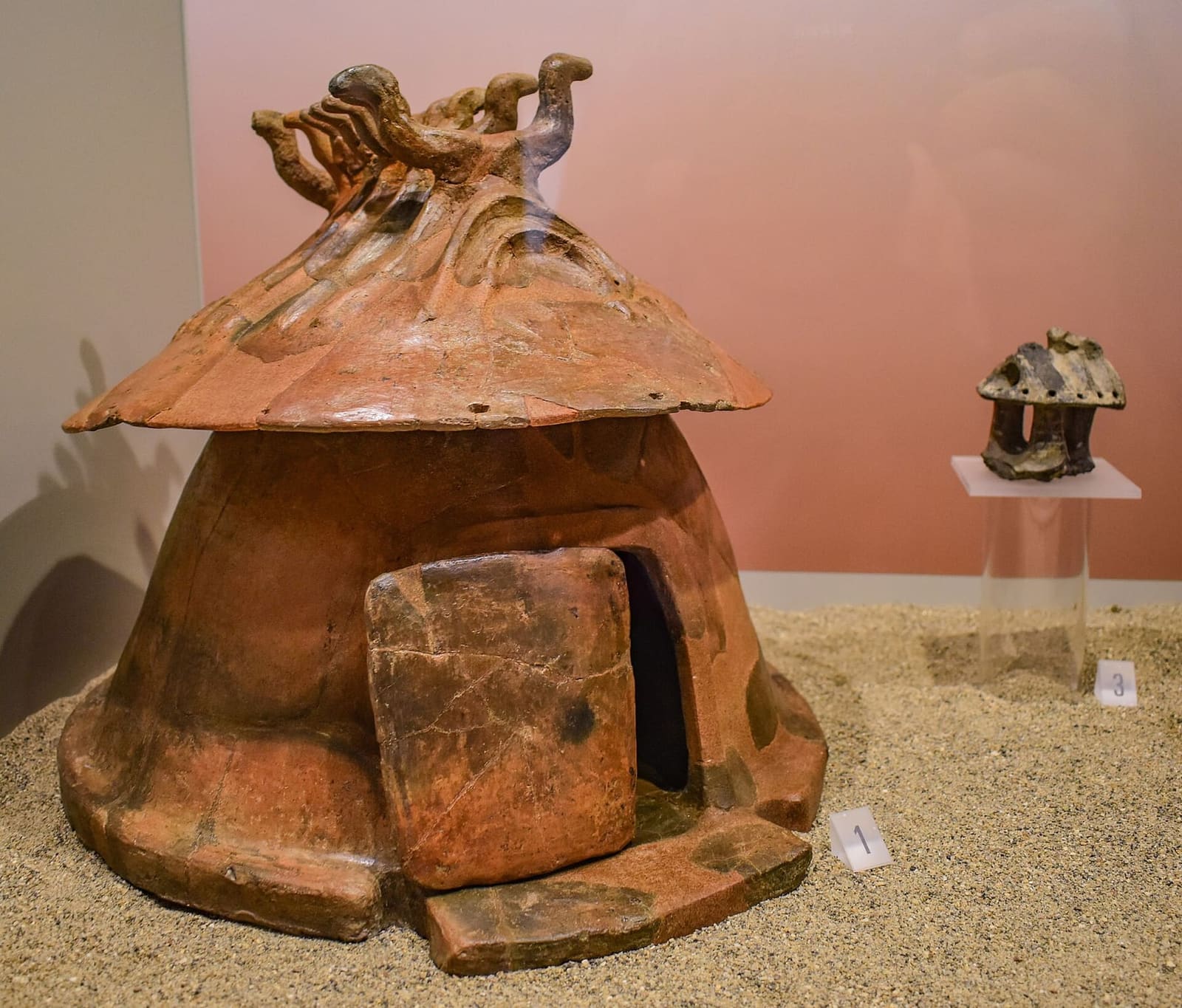 un'urna a capanna di terracotta nel museo: le ceneri del morto dentro il modello della casa, con la porta, il tetto e le travi incrociate in cima