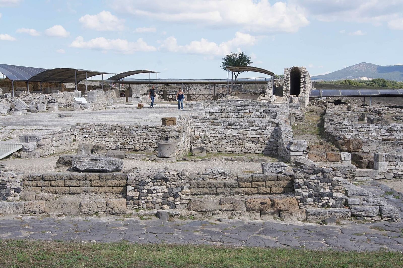 la domus del Criptoportico, la grande casa romana della città: i muri bassi delle stanze in fila, e dietro le tettoie che proteggono gli scavi