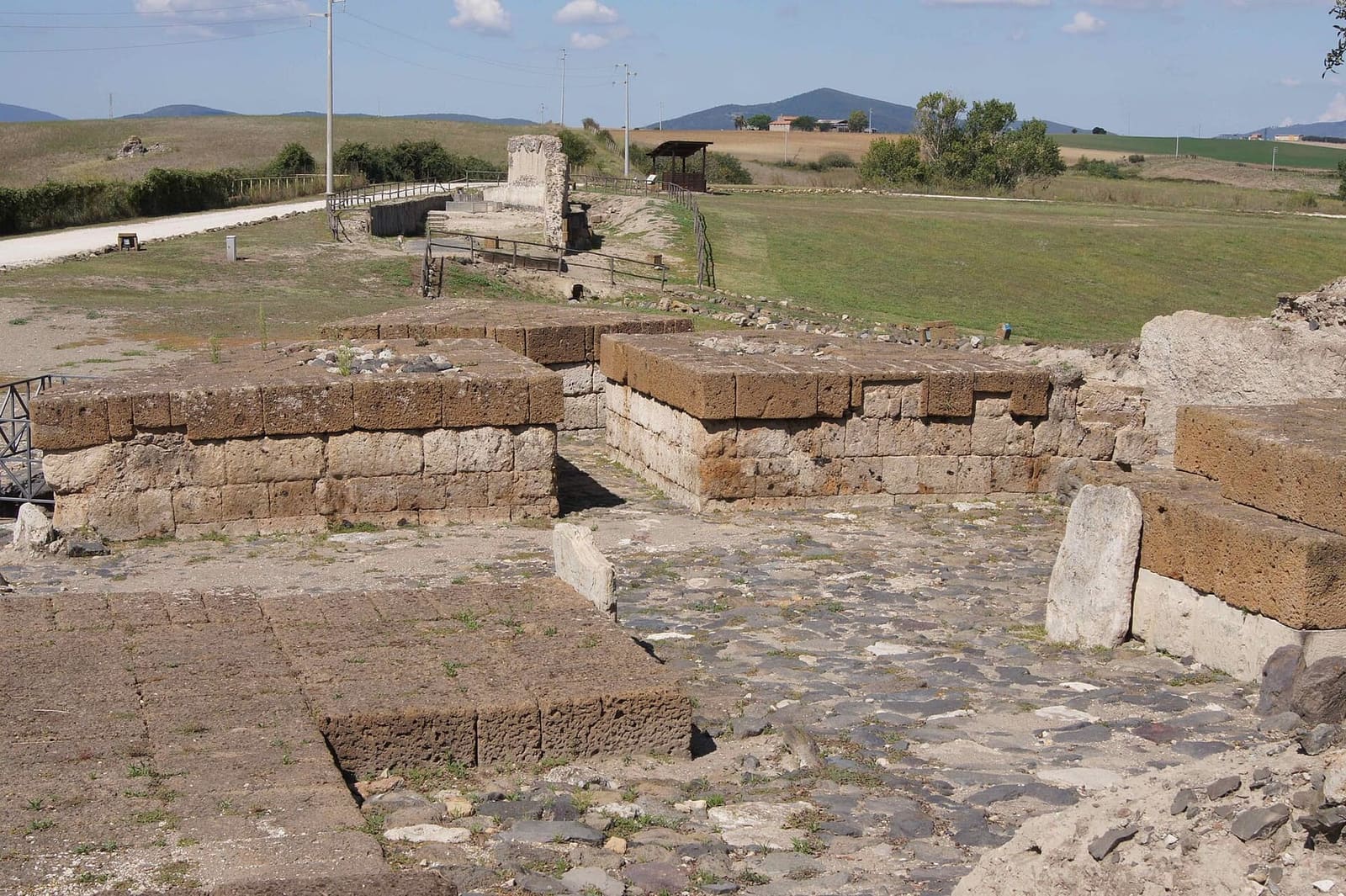 la porta ovest: i basamenti di blocchi di tufo ai due lati della strada basolata, e in fondo quello che resta dell'acquedotto