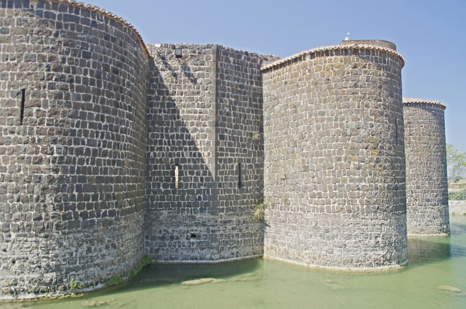 le torri tonde del castello che scendono dritte dentro il fossato pieno d'acqua