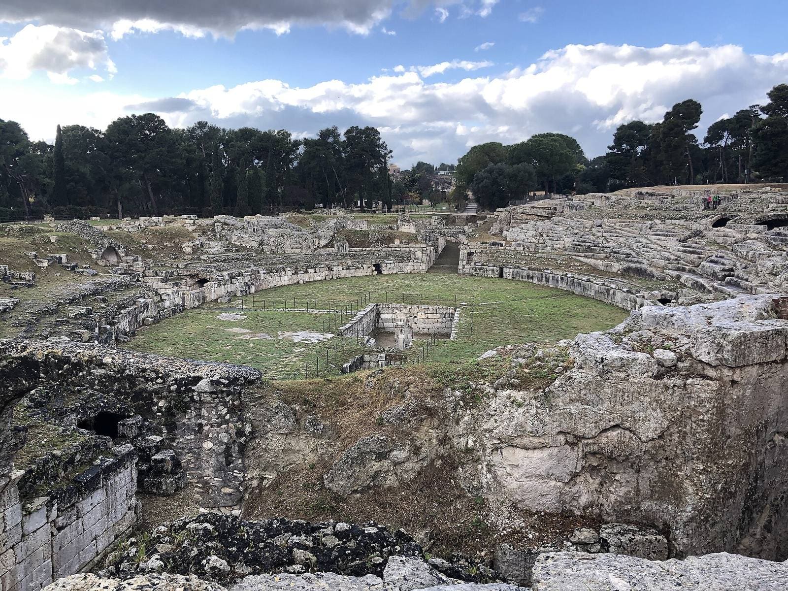 l'anfiteatro romano dall'alto, con l'arena verde e la fossa rettangolare scavata al centro