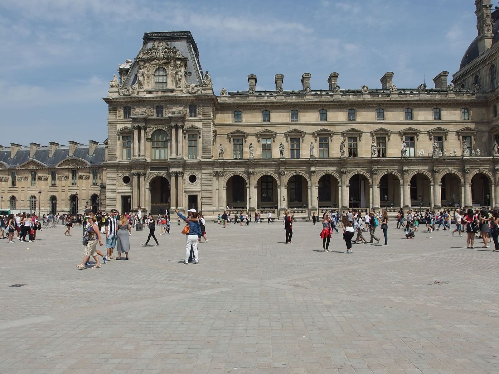 a pavilion of the Louvre and the arcades with statues on the facade, from the museum square