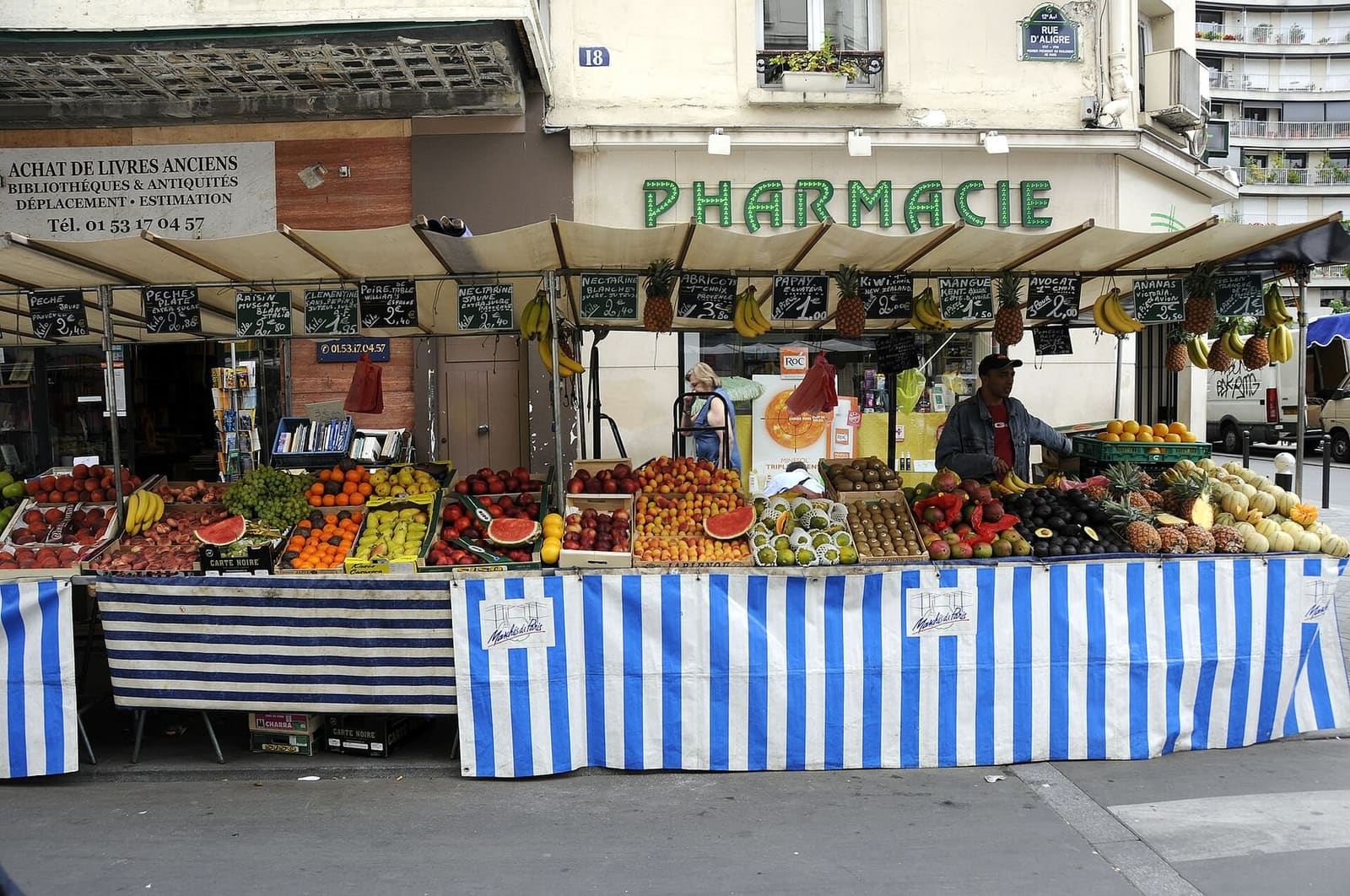 a fruit and vegetable stall under the striped awnings of the Aligre market