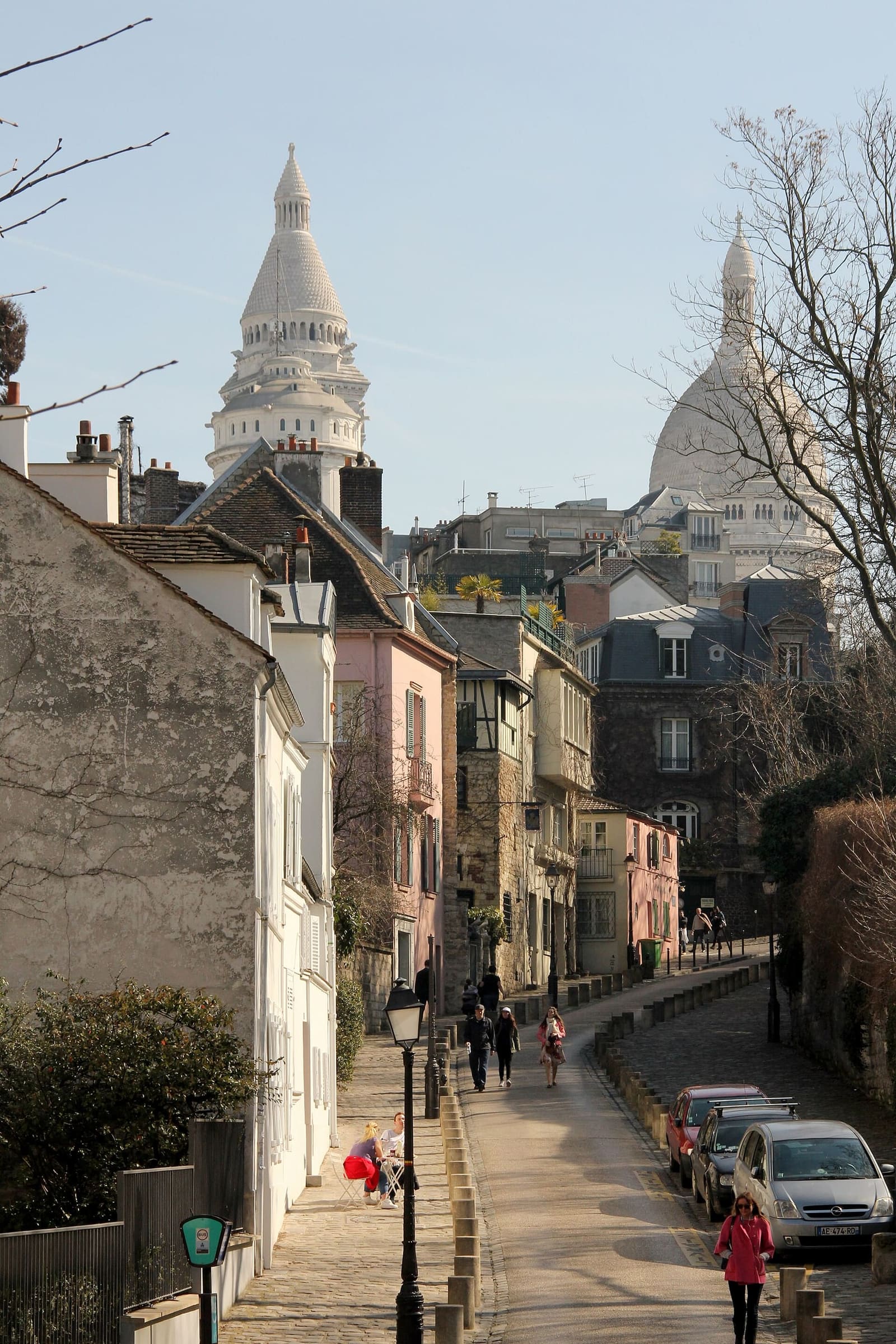Rue de l'Abreuvoir climbing between the low houses of Montmartre, with the domes of the Sacré-Cœur at the end