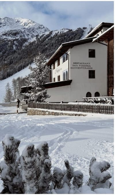 Maso Corto dopo una nevicata, con la linea dell'impianto che sale dietro le case