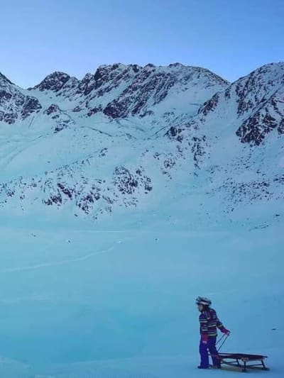 uno slittino di legno sulla neve dell'altopiano, con le creste rocciose nella luce fredda