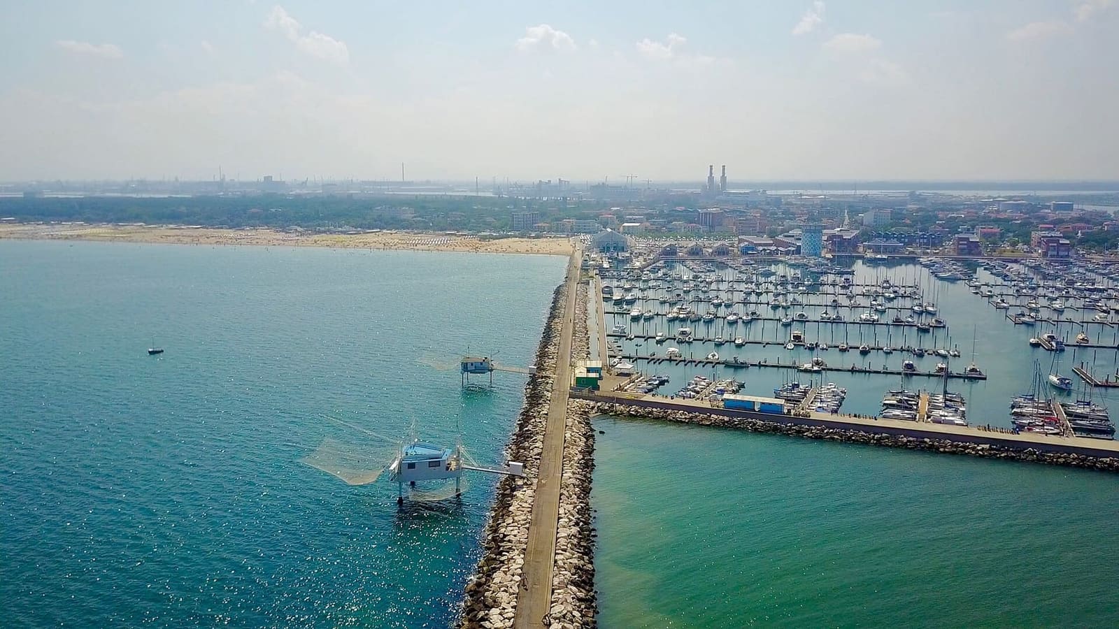 die Mole von Marina di Ravenna von oben, mit einer Fischerhütte und dem Sporthafen