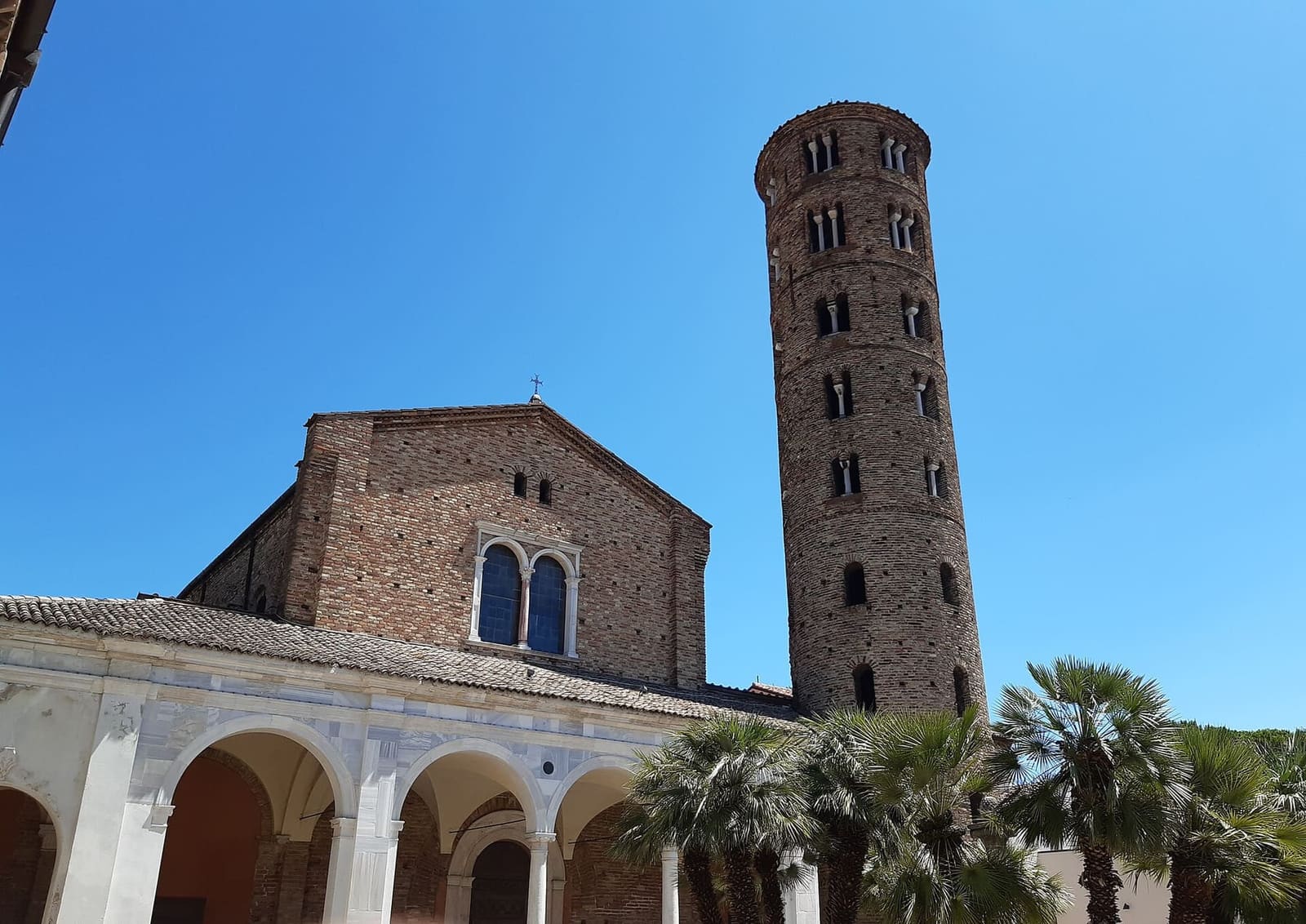 die Vorhalle und der runde Glockenturm von Sant'Apollinare Nuovo, zwischen den Palmen