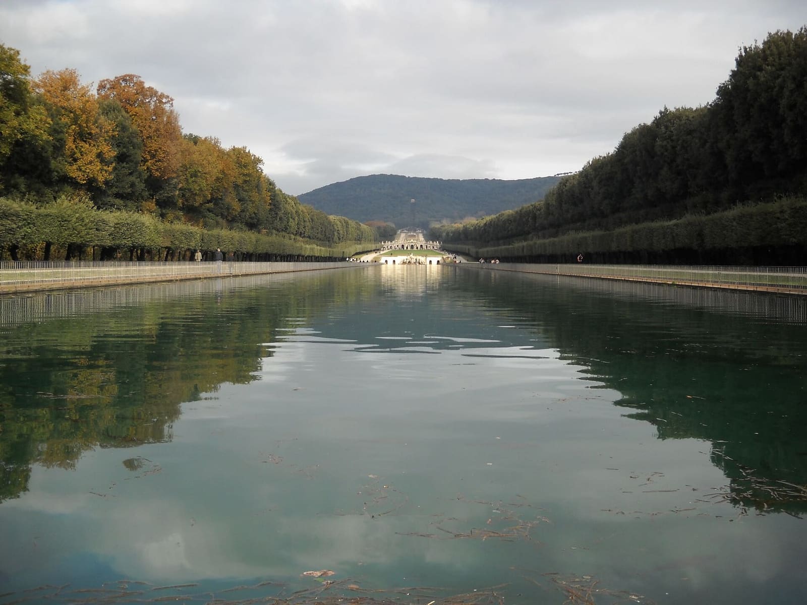 la Via d'Acqua con gli alberi d'autunno riflessi nella vasca e la cascata in fondo