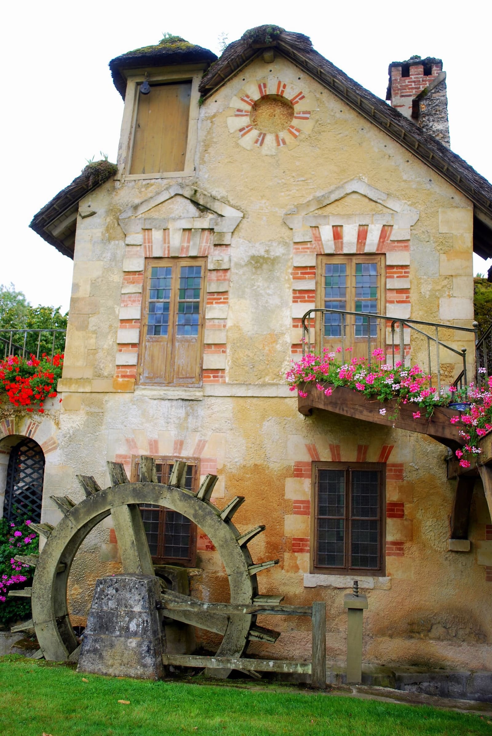 le moulin du Hameau de la Reine avec sa roue de bois et des géraniums à la fenêtre