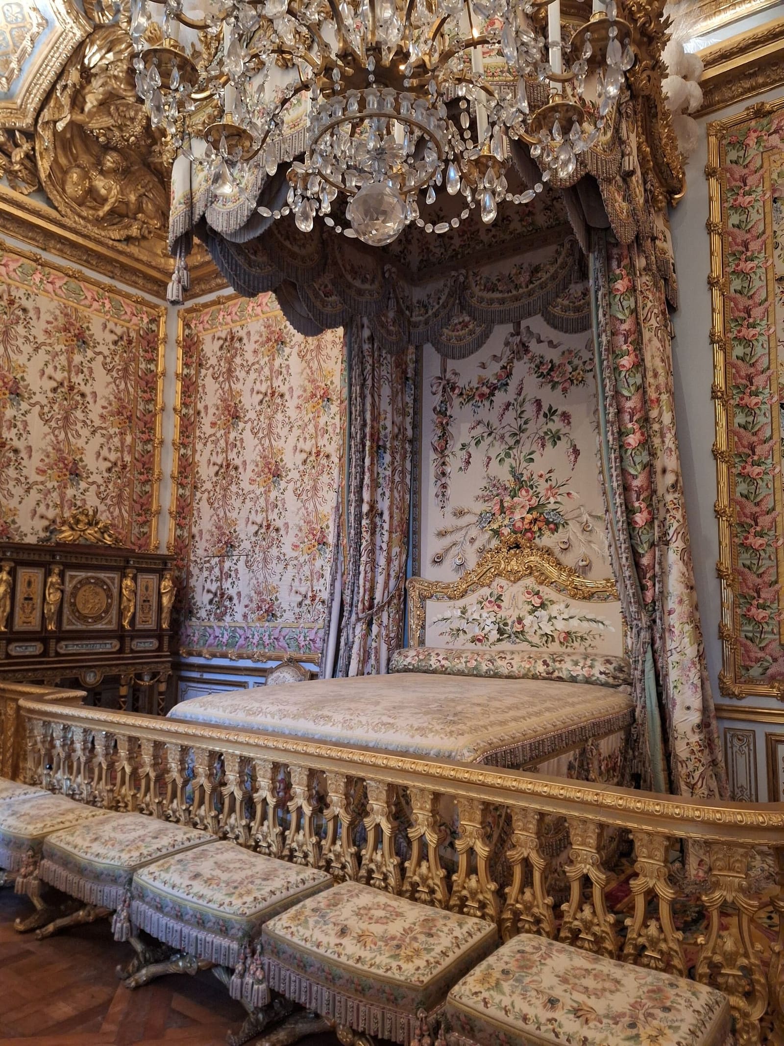 le lit à baldaquin et les étoffes fleuries de la chambre de la Reine