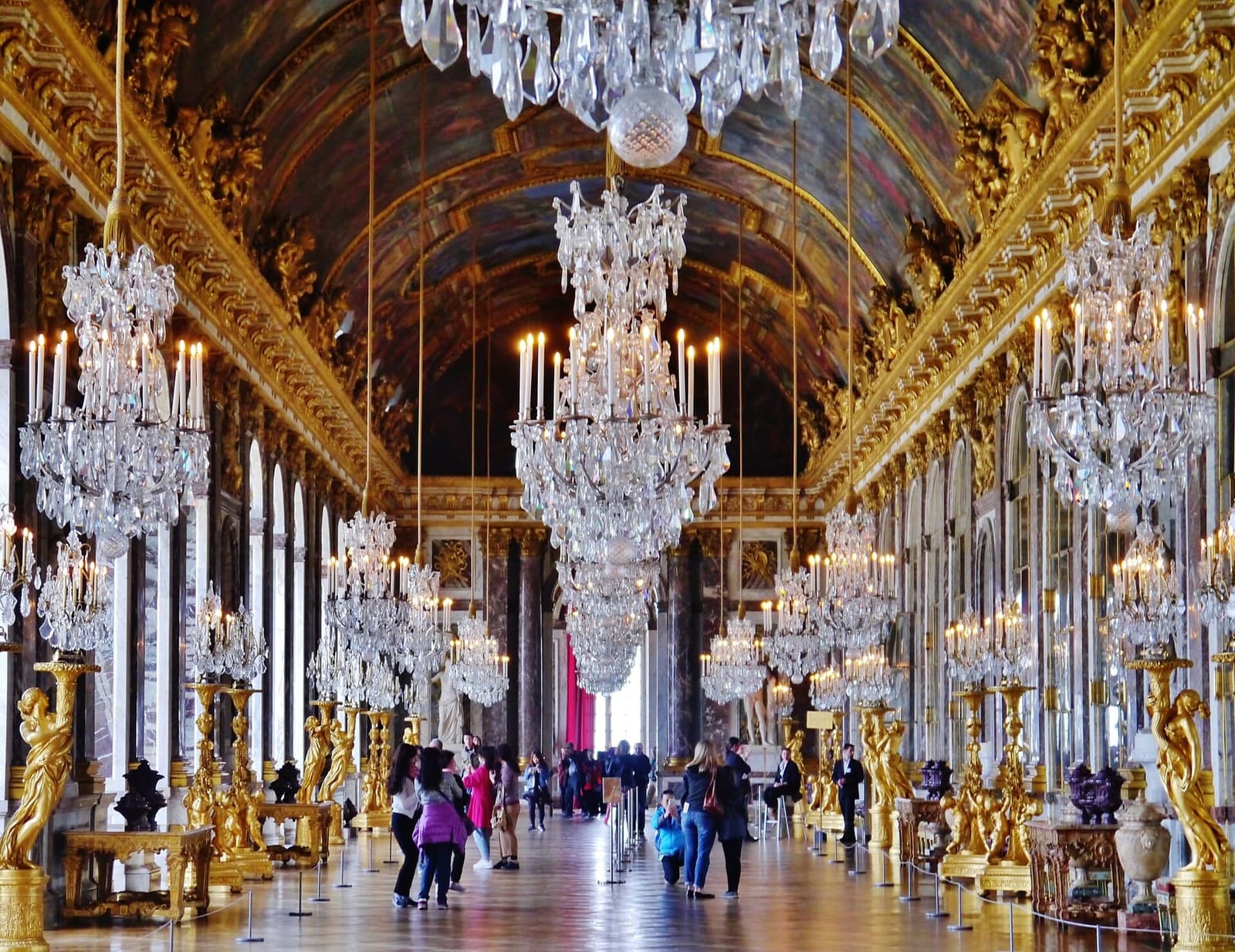 la galerie des Glaces en enfilade, avec les lustres de cristal et les torchères dorées