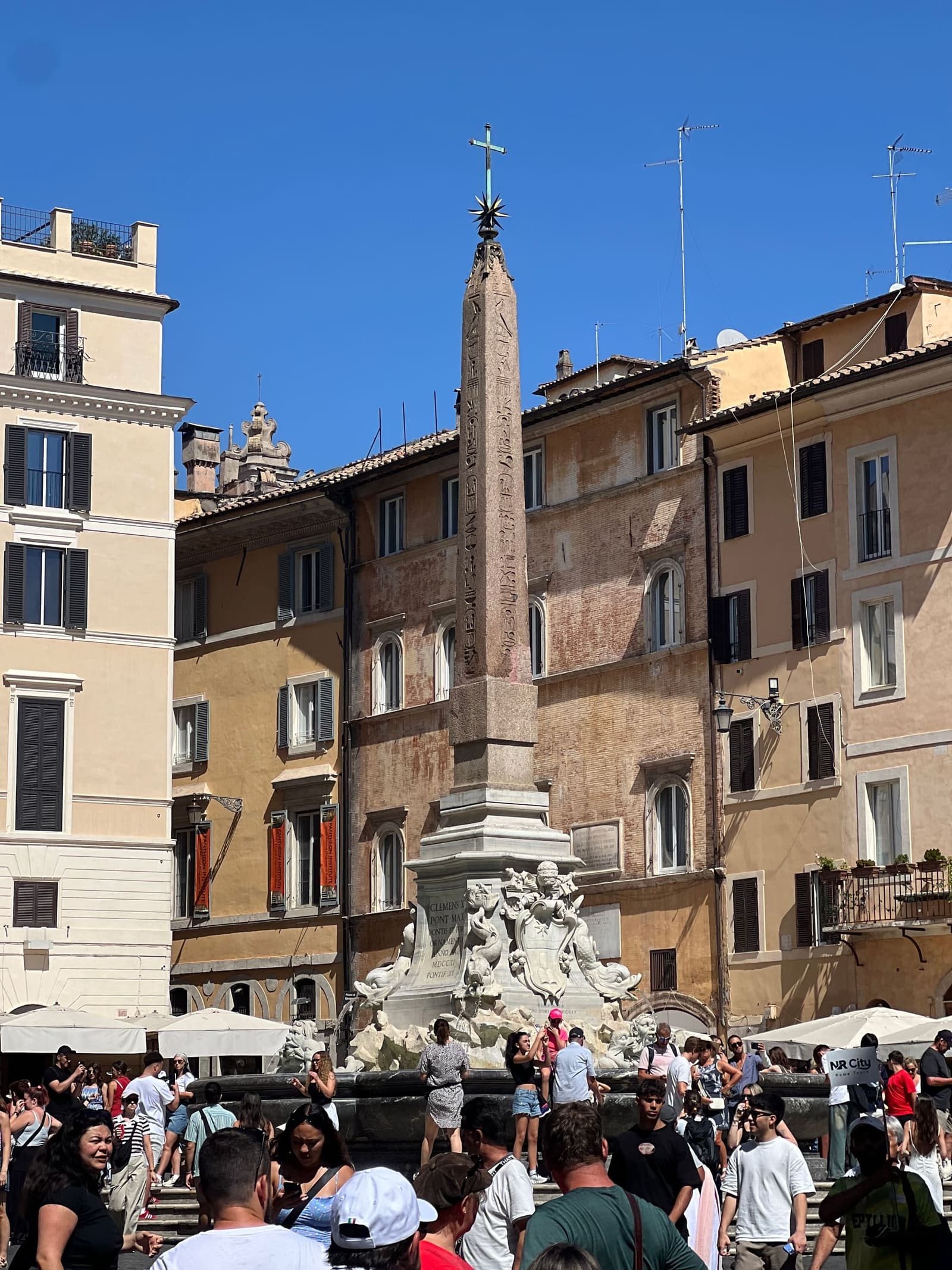 la fontana e l'obelisco Macuteo in piazza della Rotonda, con la piazza piena a mezzogiorno