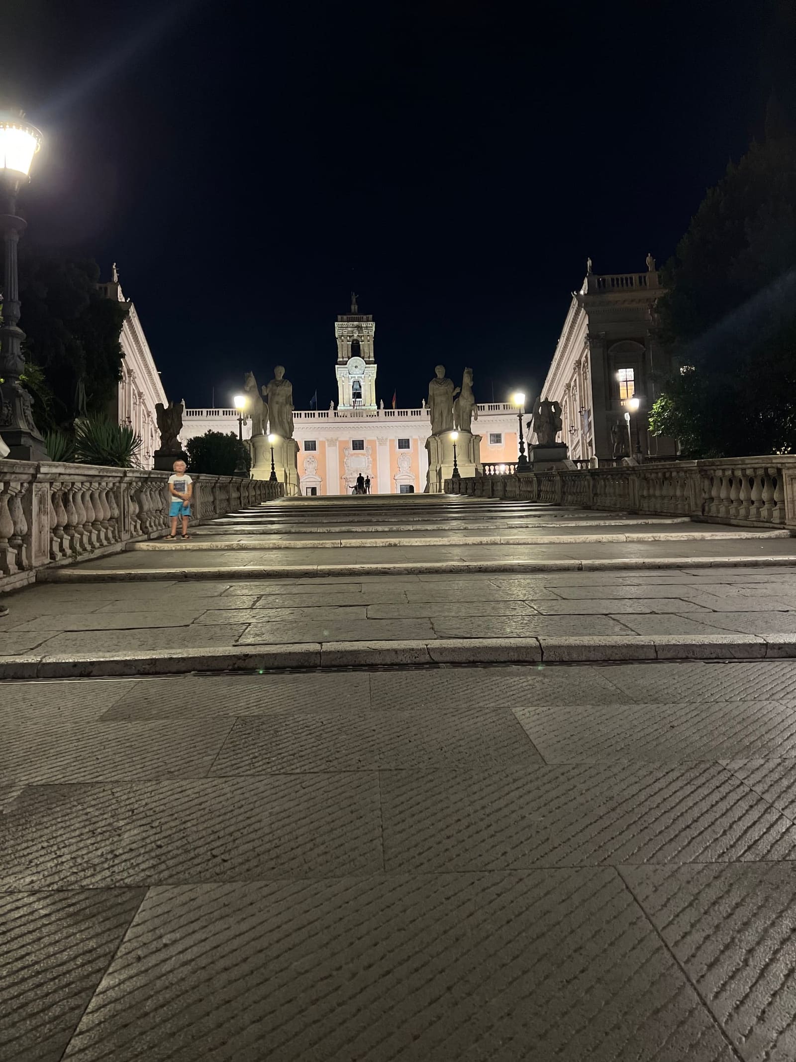 la cordonata di Michelangelo che sale al Campidoglio, di notte e vuota, con il Palazzo Senatorio in fondo