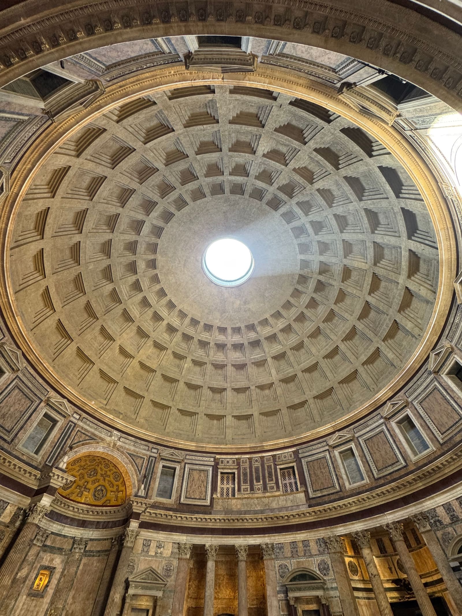 la cupola del Pantheon con i cassettoni che si rimpiccioliscono verso l'oculo, e il buco di nove metri che è l'unica luce