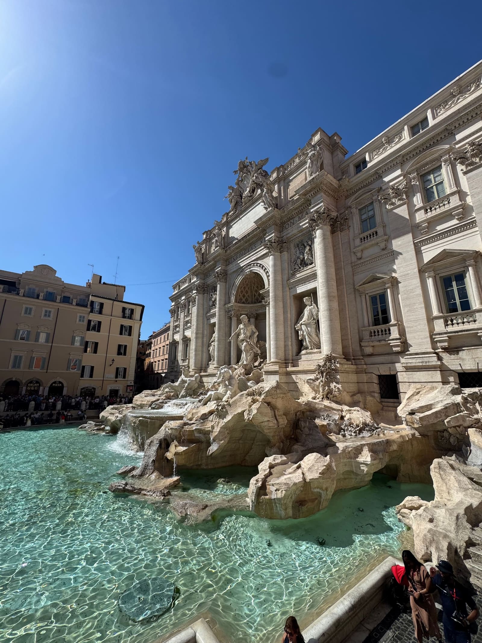 la Fontana di Trevi di scorcio nel primo pomeriggio, con l'acqua verde e la luce piena sui marmi