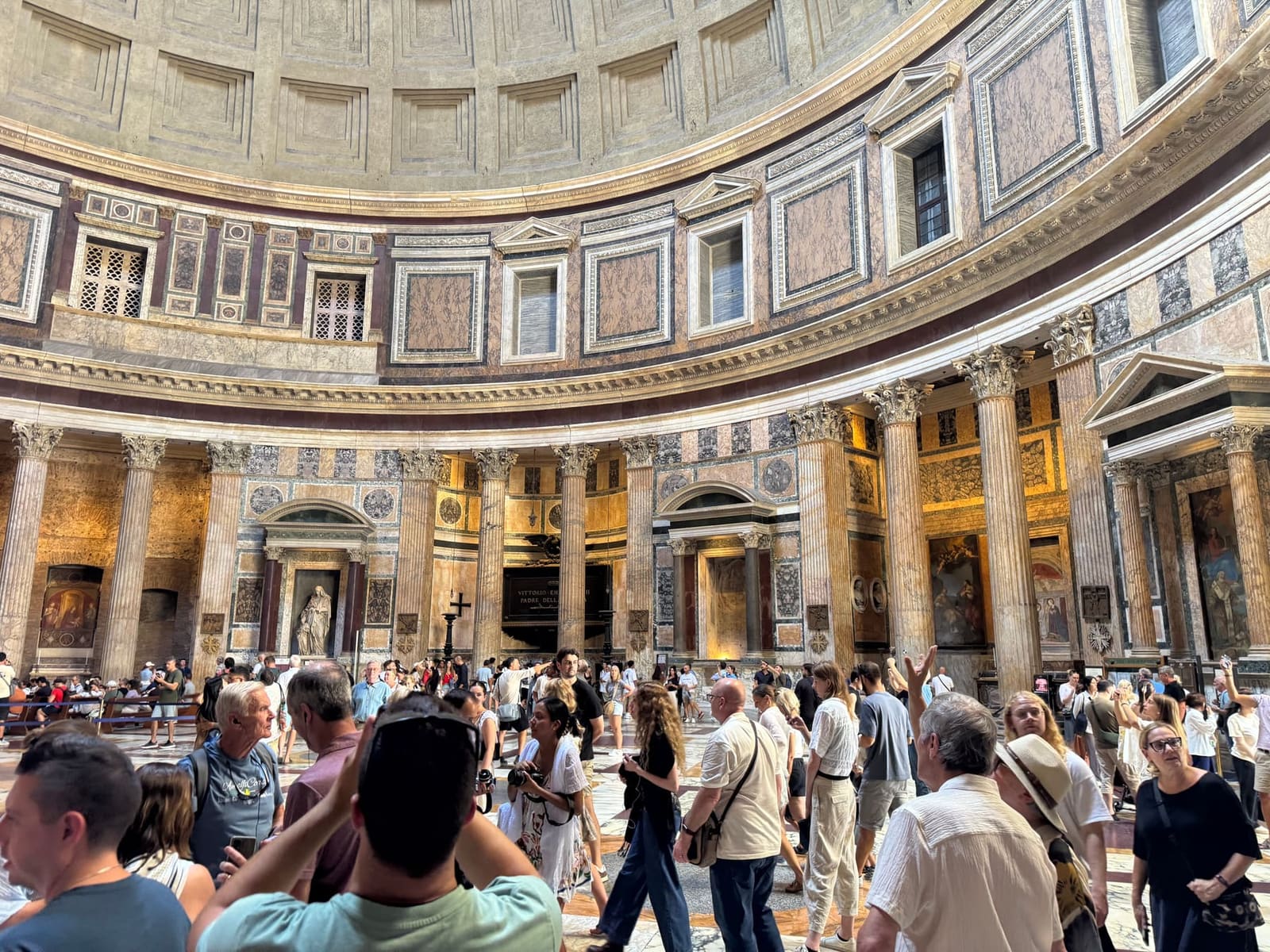 la rotonda del Pantheon vista dall'interno, con la gente che gira sotto le nicchie e i telefoni tutti puntati in alto