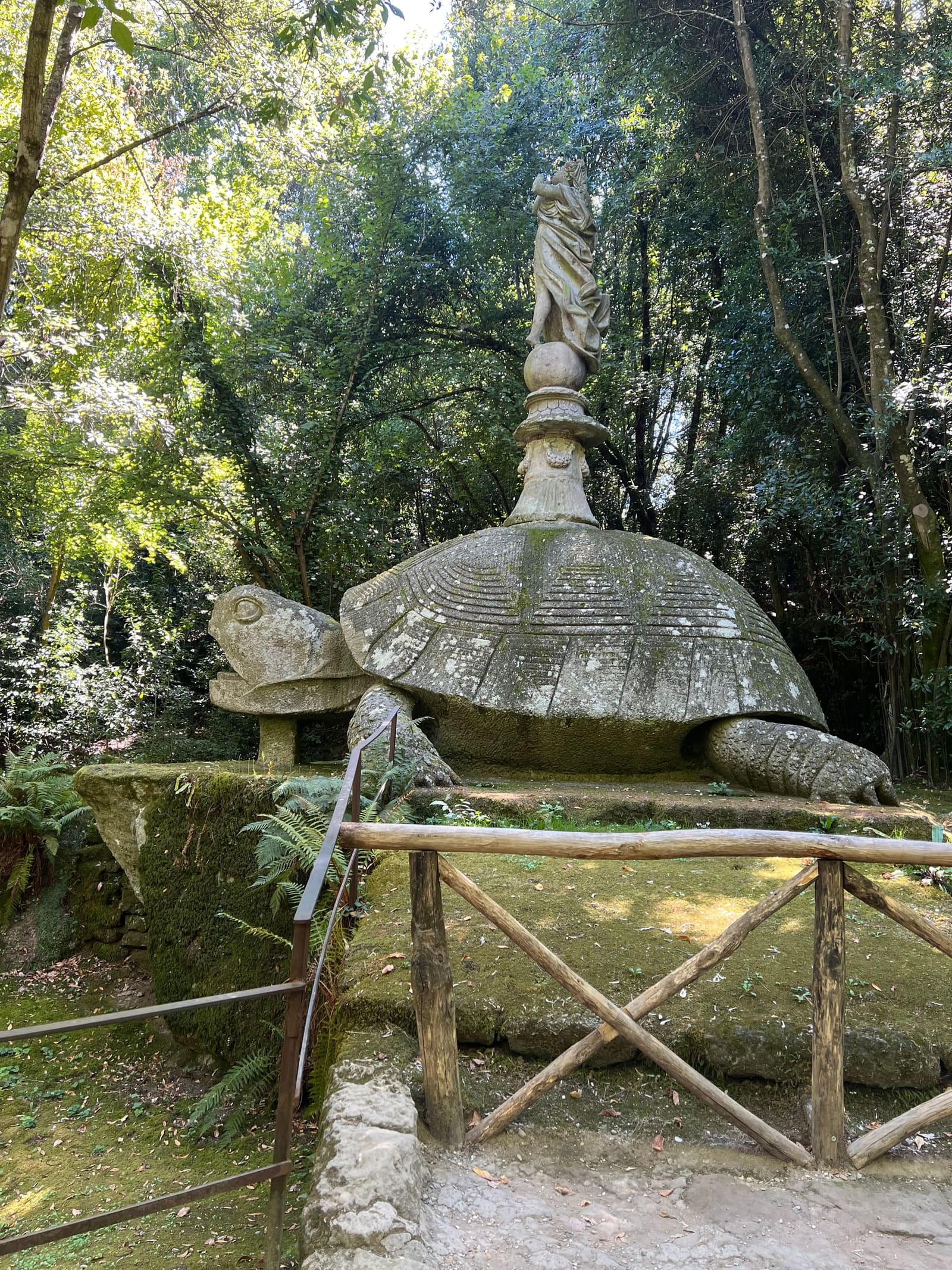 la tartaruga gigante con la figura in equilibrio sul guscio, e dietro la testa della balena che spunta dal verde