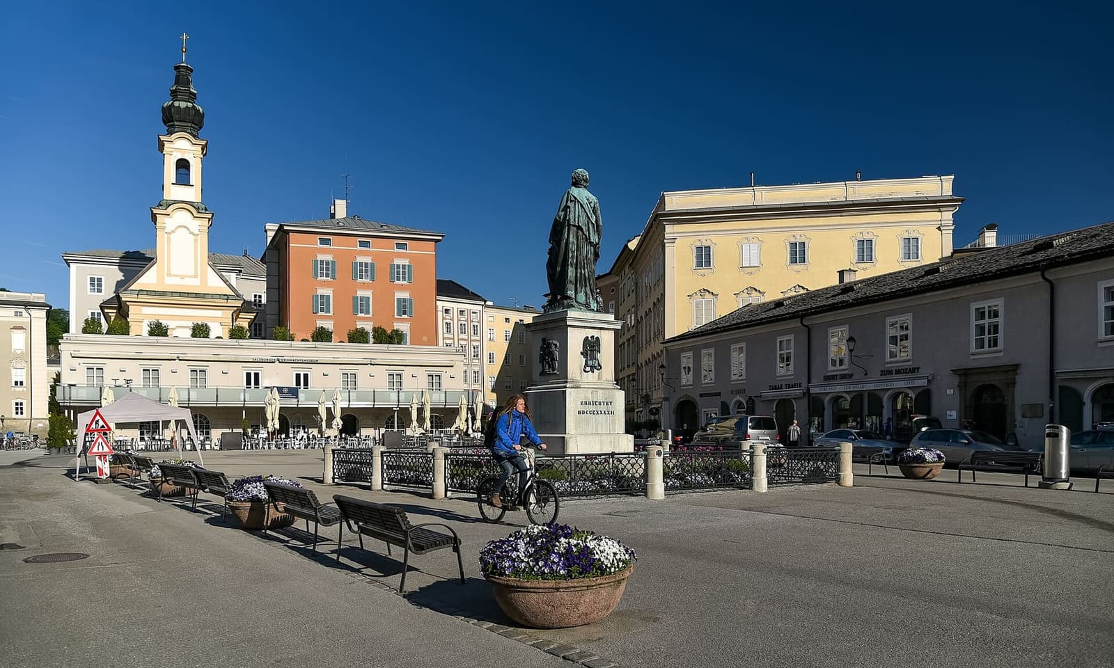 la statua di Mozart sulla Mozartplatz, con la chiesa di San Michele dietro