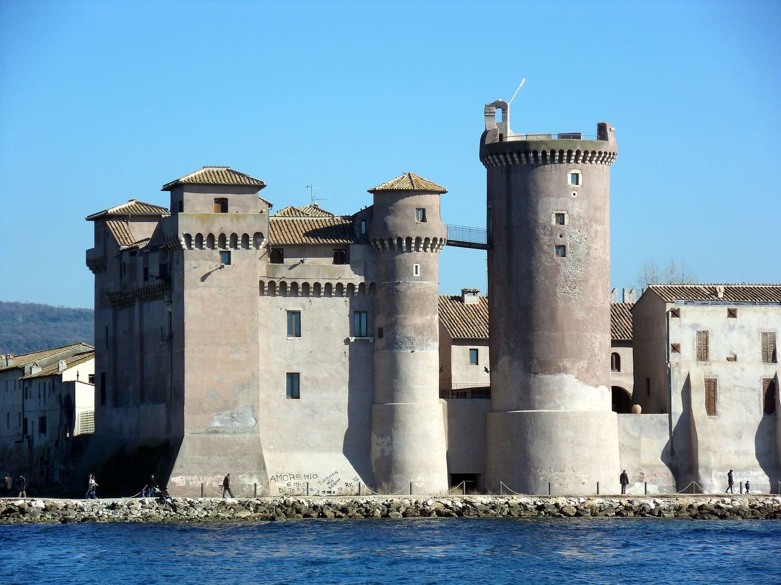 la Rocca e la Torre Saracena viste dal mare, unite in alto da una passerella di ferro, con la scogliera sotto le mura