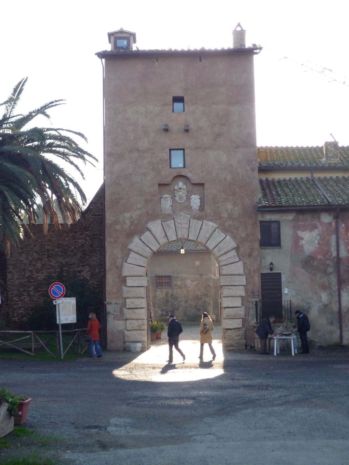 la torre della porta da cui si entra nel complesso, con gli stemmi sopra l'arco di pietra e il cortile che si intravede dentro