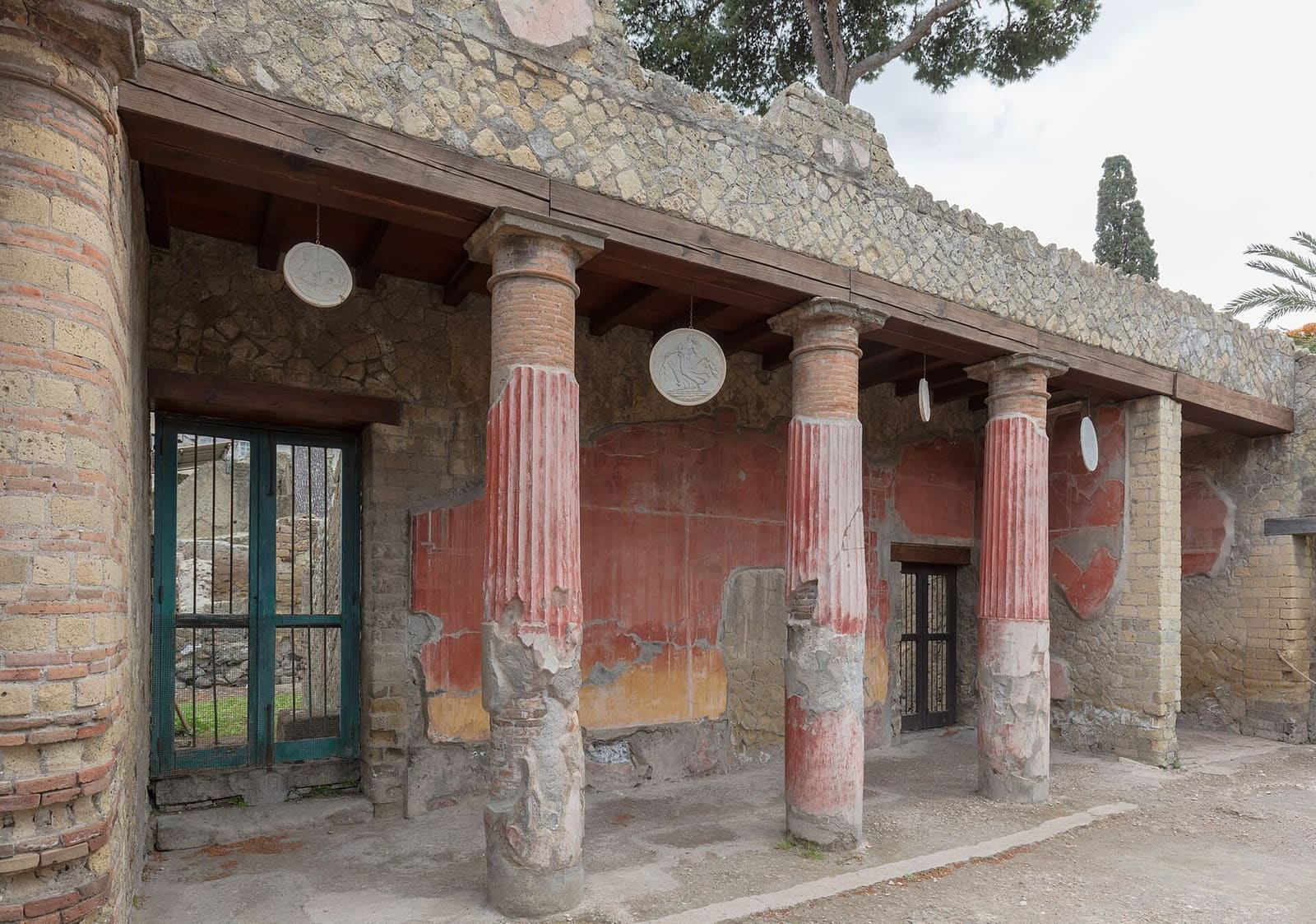 il portico con le colonne rosse della Casa del Rilievo di Telefo, con i dischi appesi