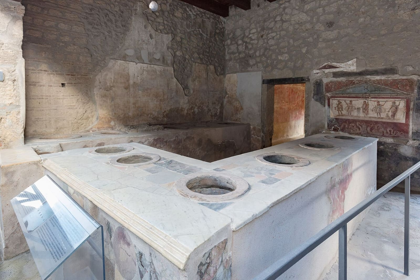 il bancone con i vasi incassati del thermopolium di Vetutius Placidus, e il larario dipinto, a marzo
