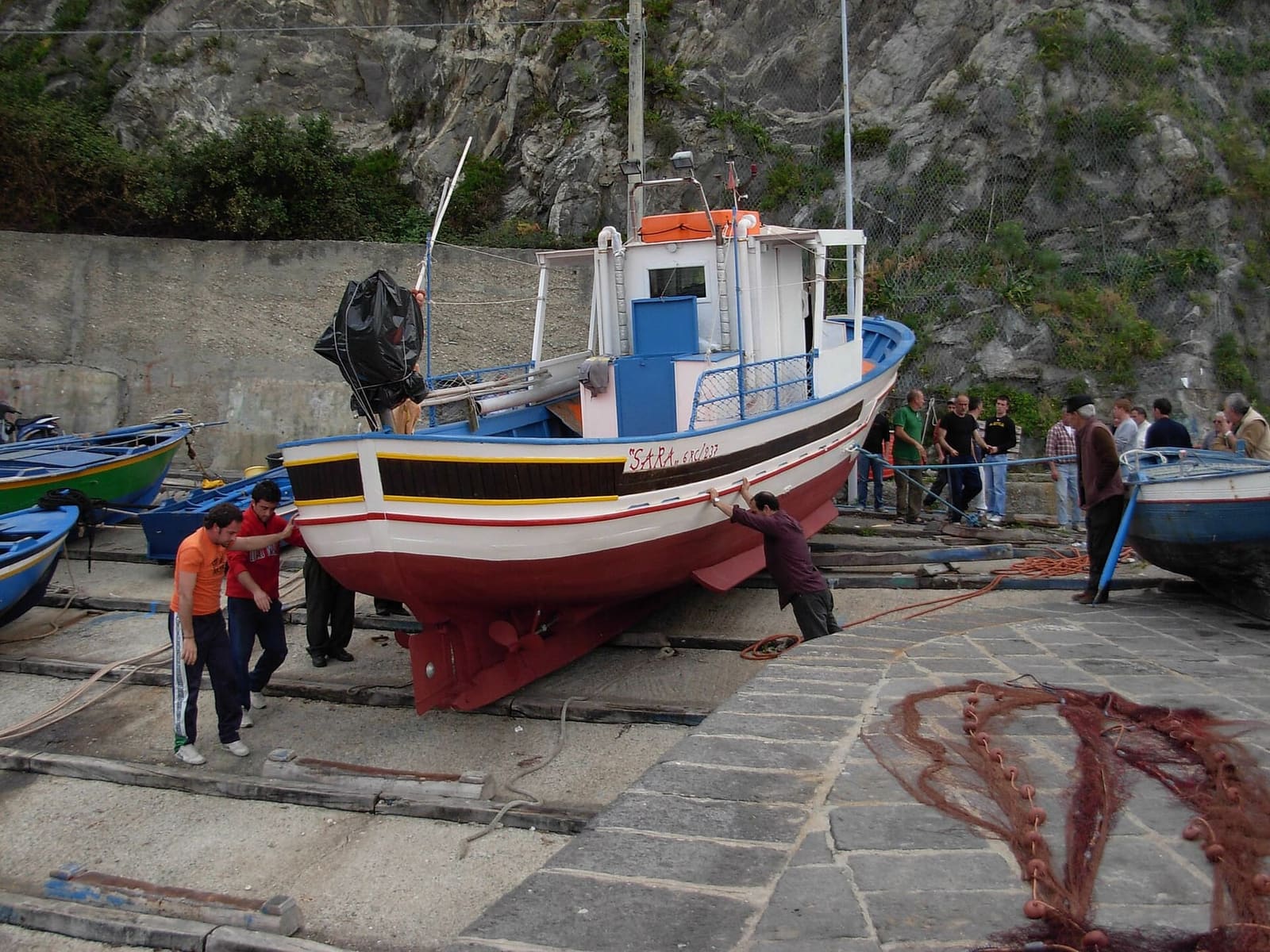i pescatori spingono in mare una barca dallo scalo sotto il castello