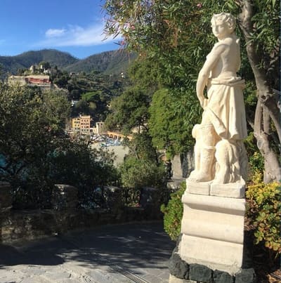 la statua sulla discesa lastricata dell'ultimo tratto, con la spiaggia di Monterosso in fondo