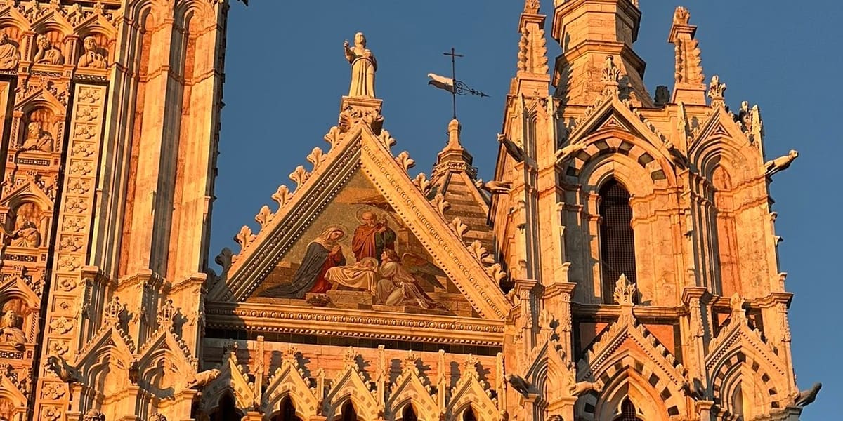 la cuspide del Duomo con il mosaico del timpano, accesa dal sole basso