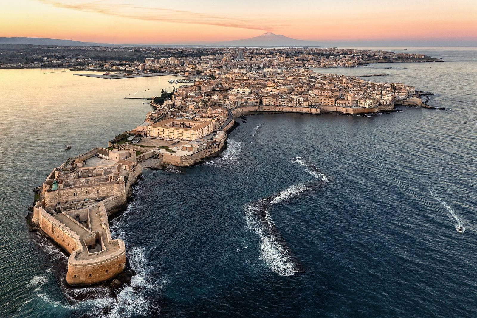 Ortigia von oben bei Sonnenuntergang, mit dem Castello Maniace an der Spitze, dem Porto Grande links und dem Ätna am Horizont