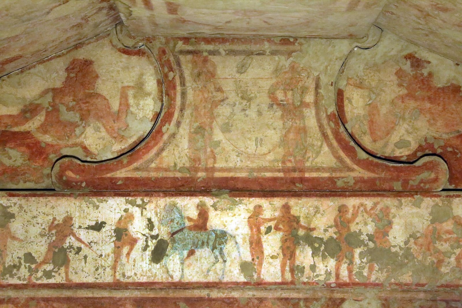 il fregio della Tomba delle Bighe al museo: sotto il timpano corrono i giochi funebri, atleti, lottatori e un cavaliere sul cavallo azzurro