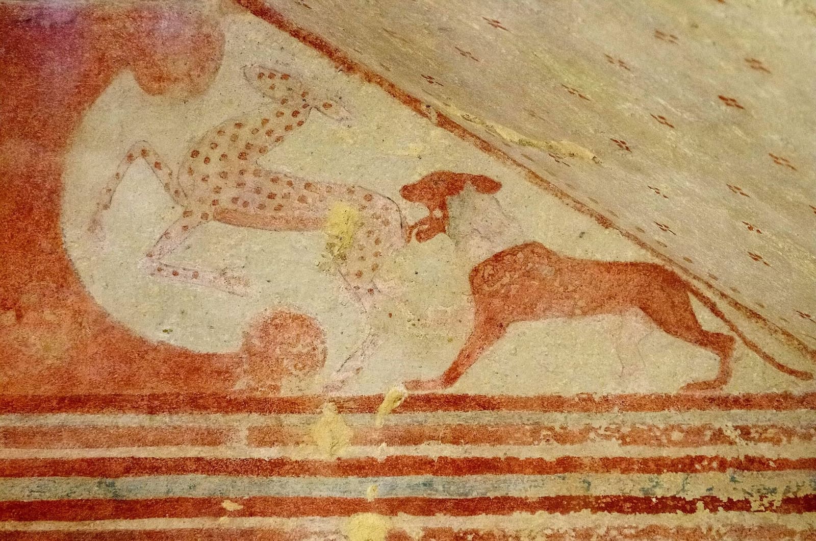 il timpano della Tomba dei Baccanti da vicino: un leone si avventa su un'antilope maculata, dentro la voluta rossa