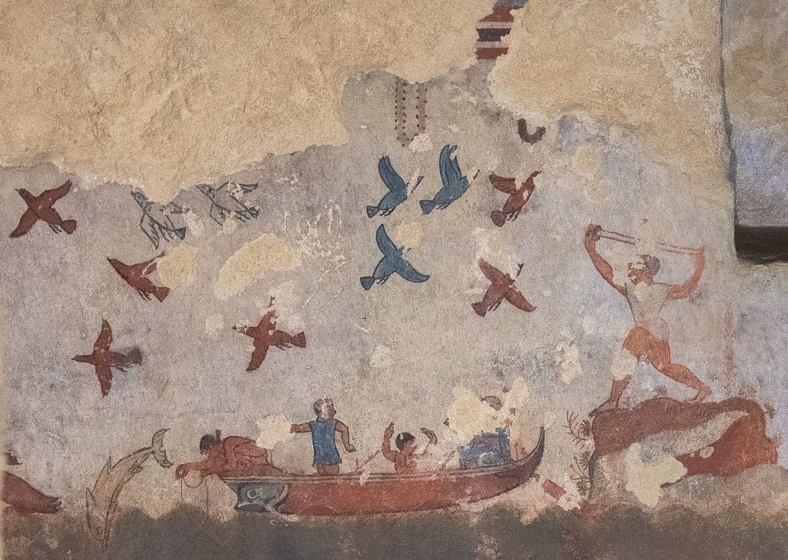 la parete di fondo della Tomba della Caccia e Pesca: una barca con i pescatori, uno che cala la lenza, gli uccelli rossi e azzurri in volo, e sullo scoglio un cacciatore con la fionda