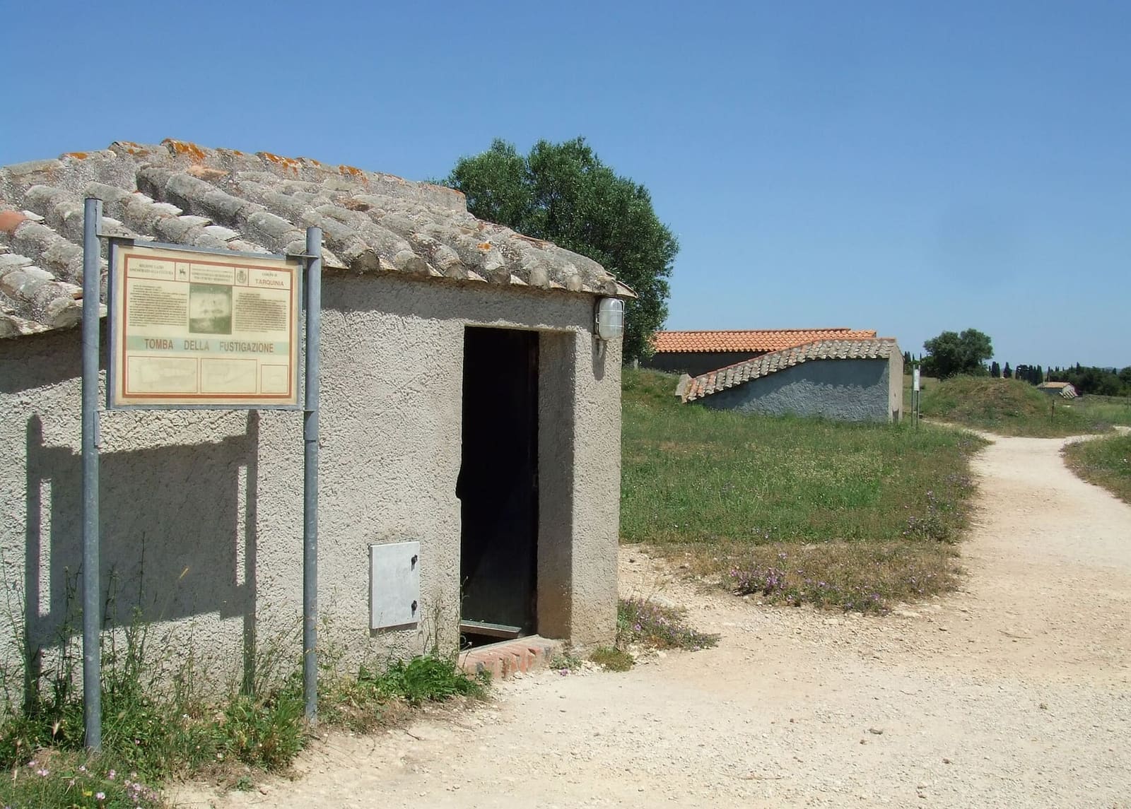 la porta aperta del casotto della Tomba della Fustigazione, e il sentiero bianco che porta al casotto dopo