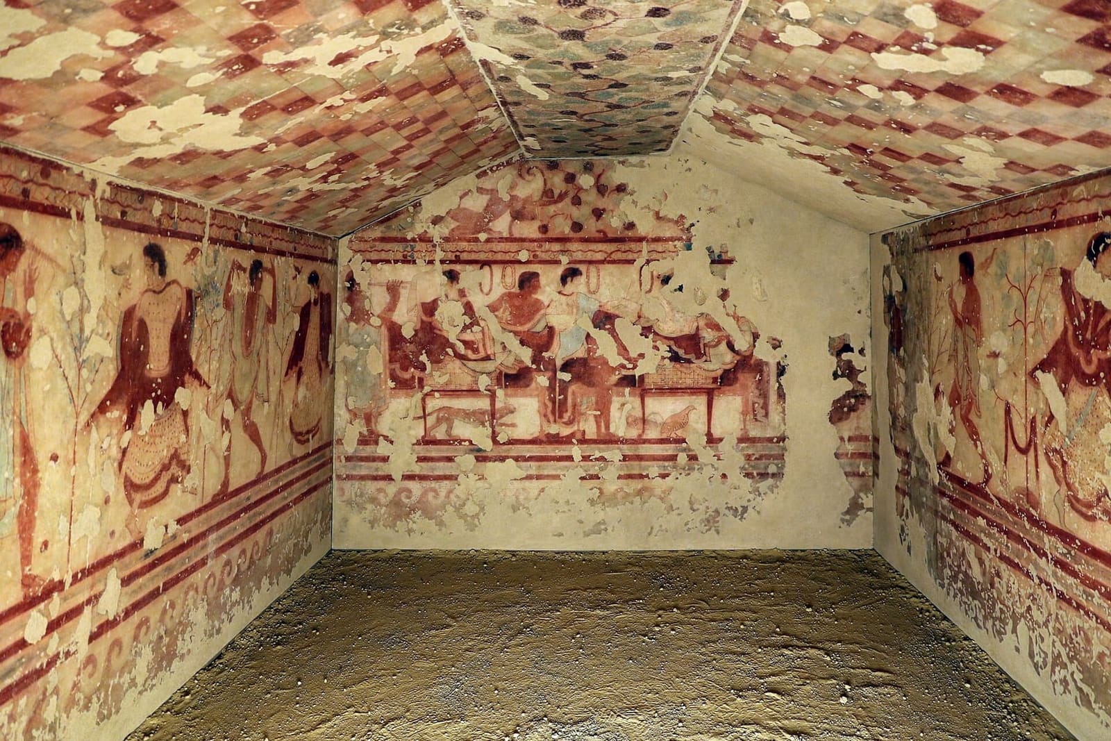 la Tomba del Triclinio rimontata al museo con i dipinti staccati: il banchetto sulla parete di fondo, con un gatto e una pernice sotto i letti, e i danzatori e i suonatori sulle pareti ai lati