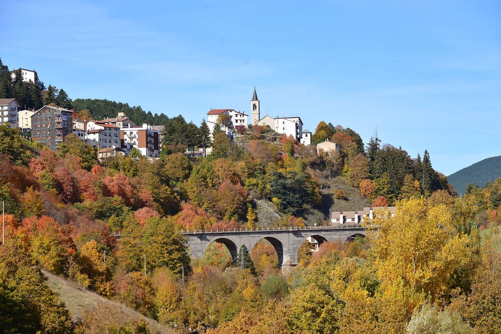Roccaraso in autumn, with the arched viaduct among the woods below the village