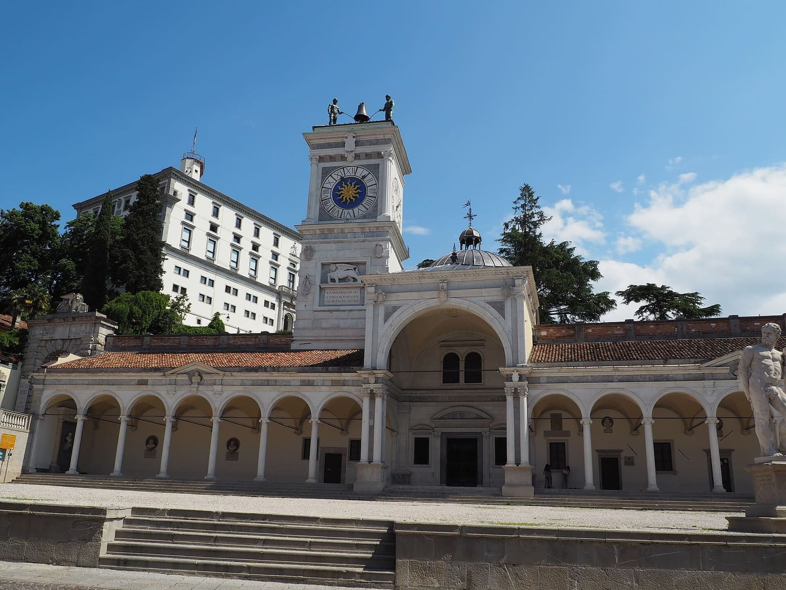 die piazza della Libertà mit dem Laubengang von San Giovanni, der Torre dell'Orologio und der Burg auf dem Hügel