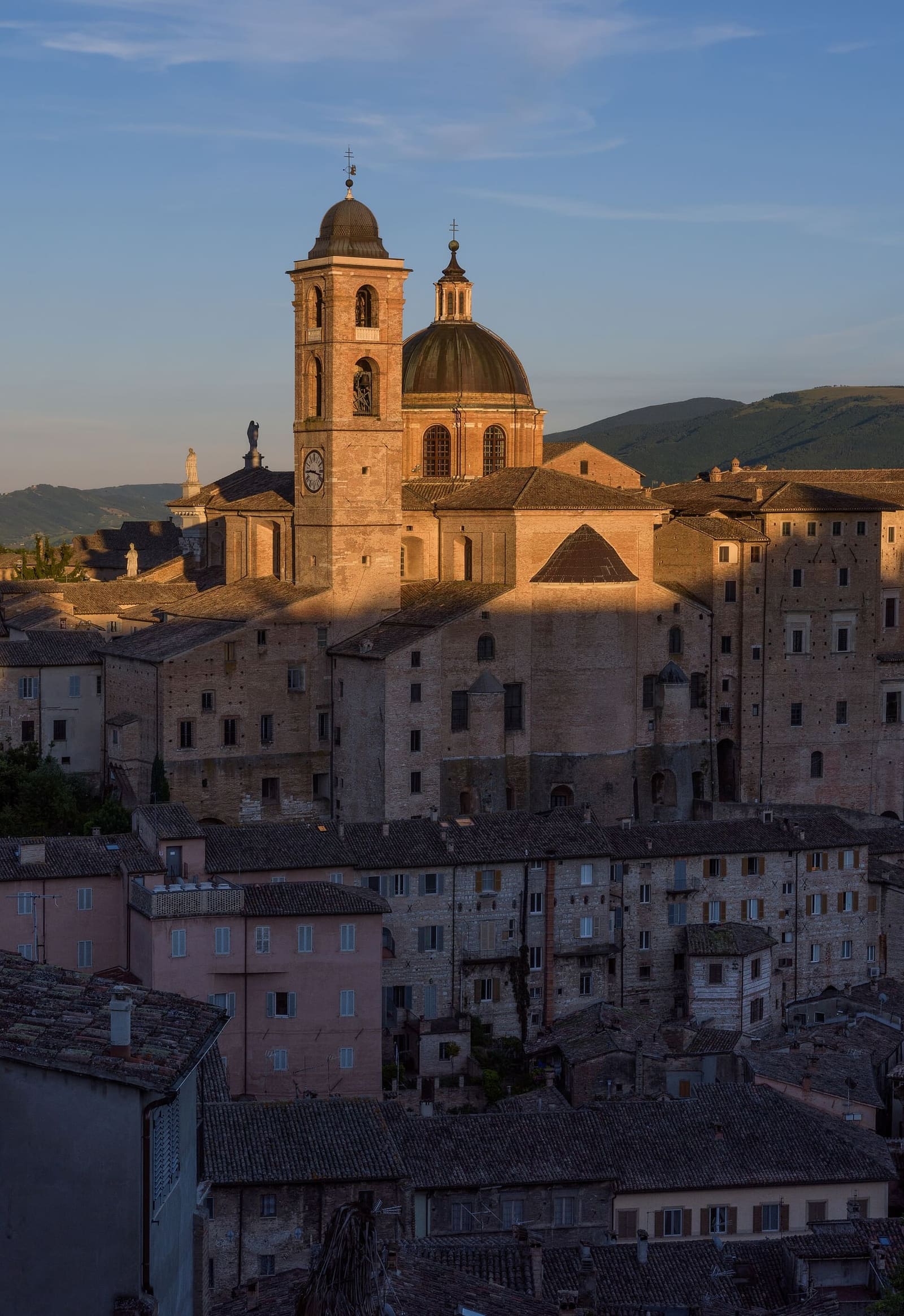 il campanile e la cupola del duomo al tramonto, sopra le case di mattoni