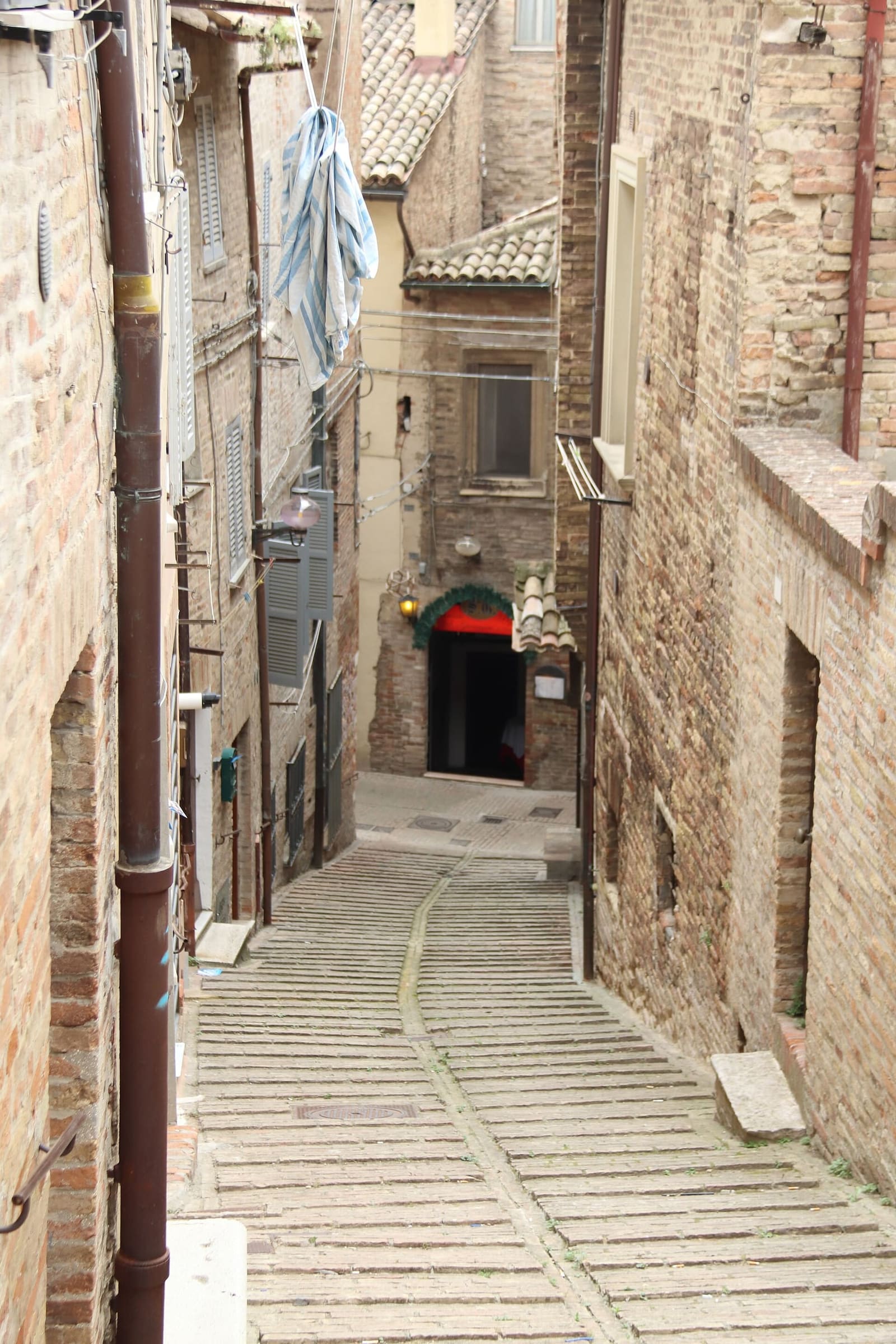 un vicolo a gradoni fra i muri di mattoni, che scende stretto verso il basso