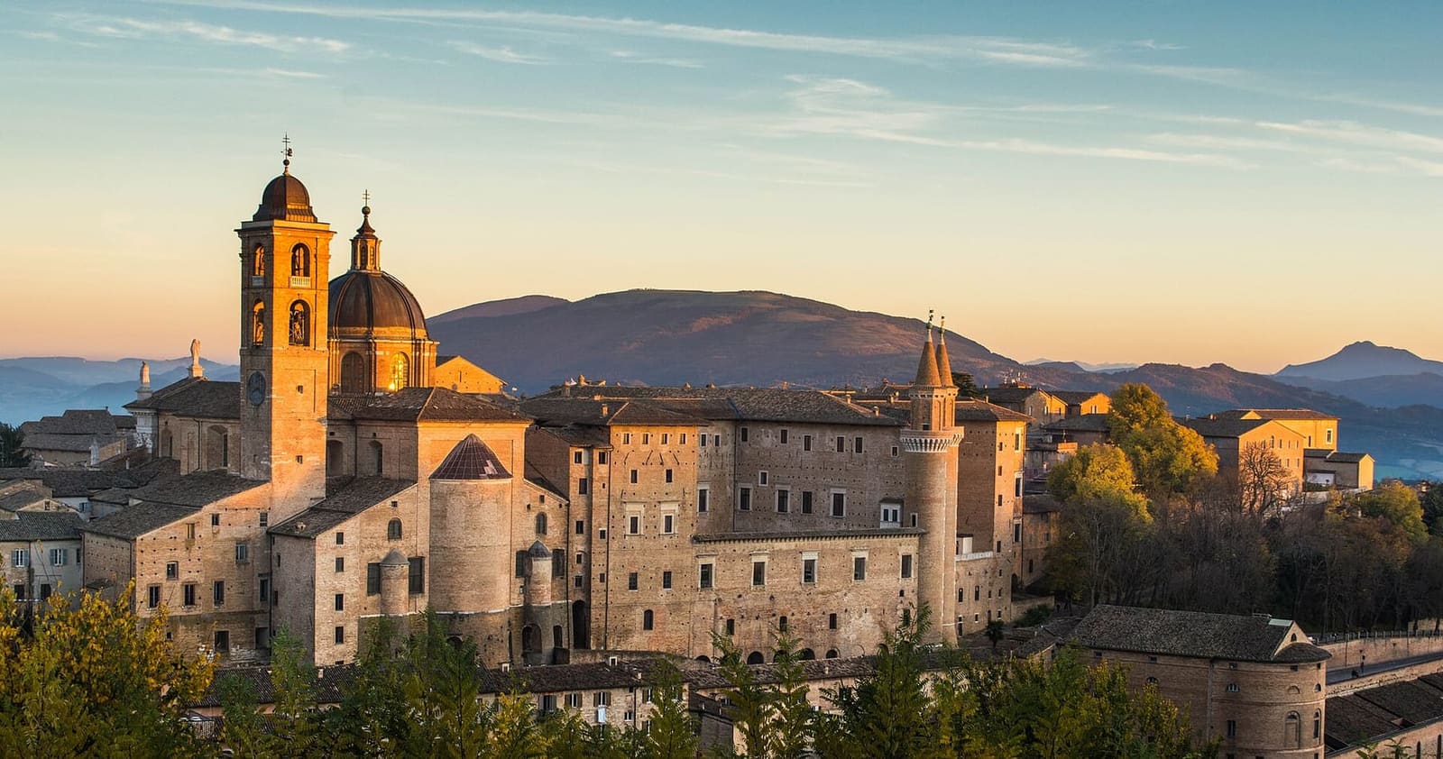 il duomo e il Palazzo Ducale sul colle nella luce radente, con l'Appennino dietro
