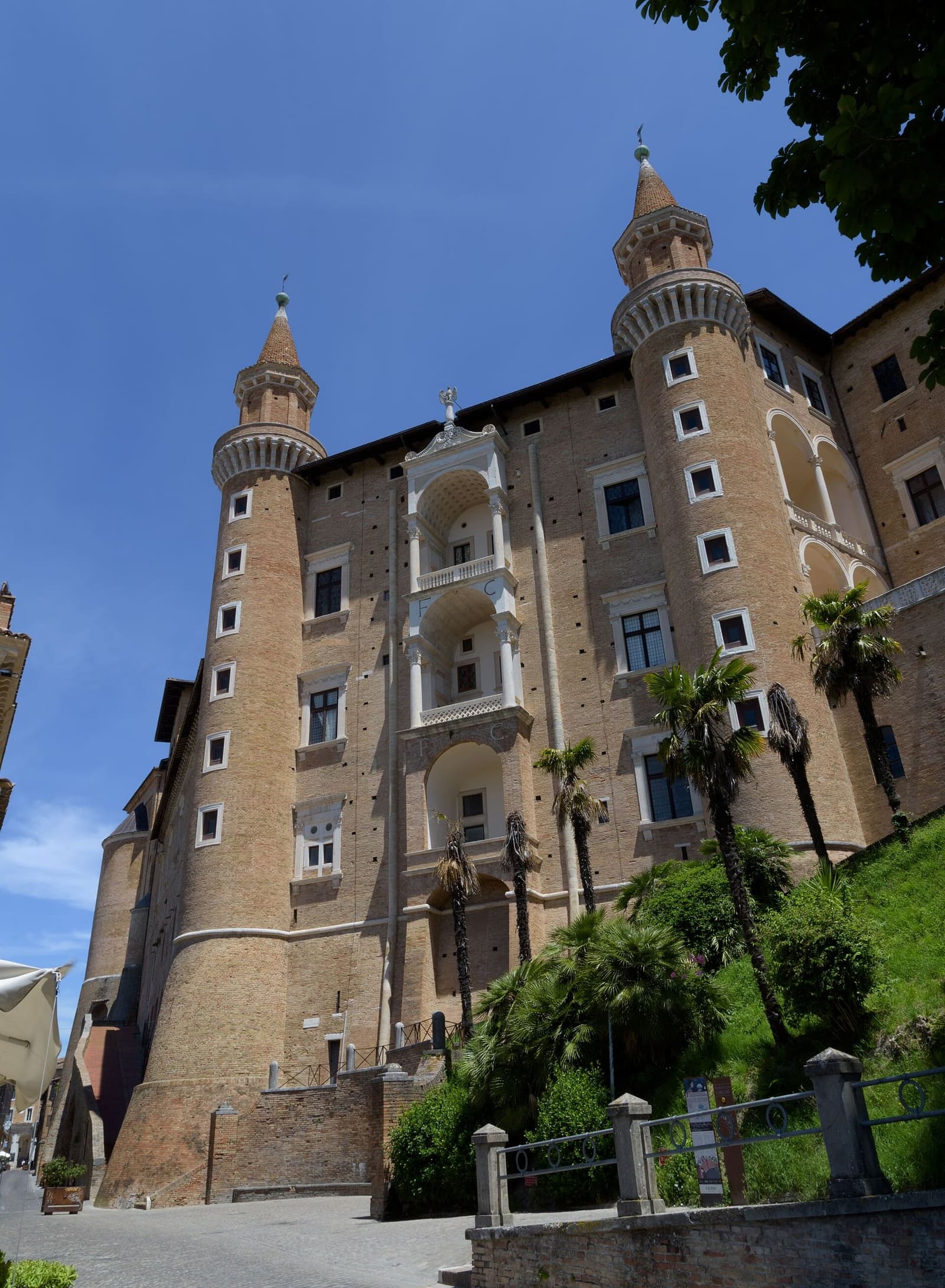 la facciata dei torricini vista da sotto, con le tre logge sovrapposte fra le due torri e le palme ai piedi