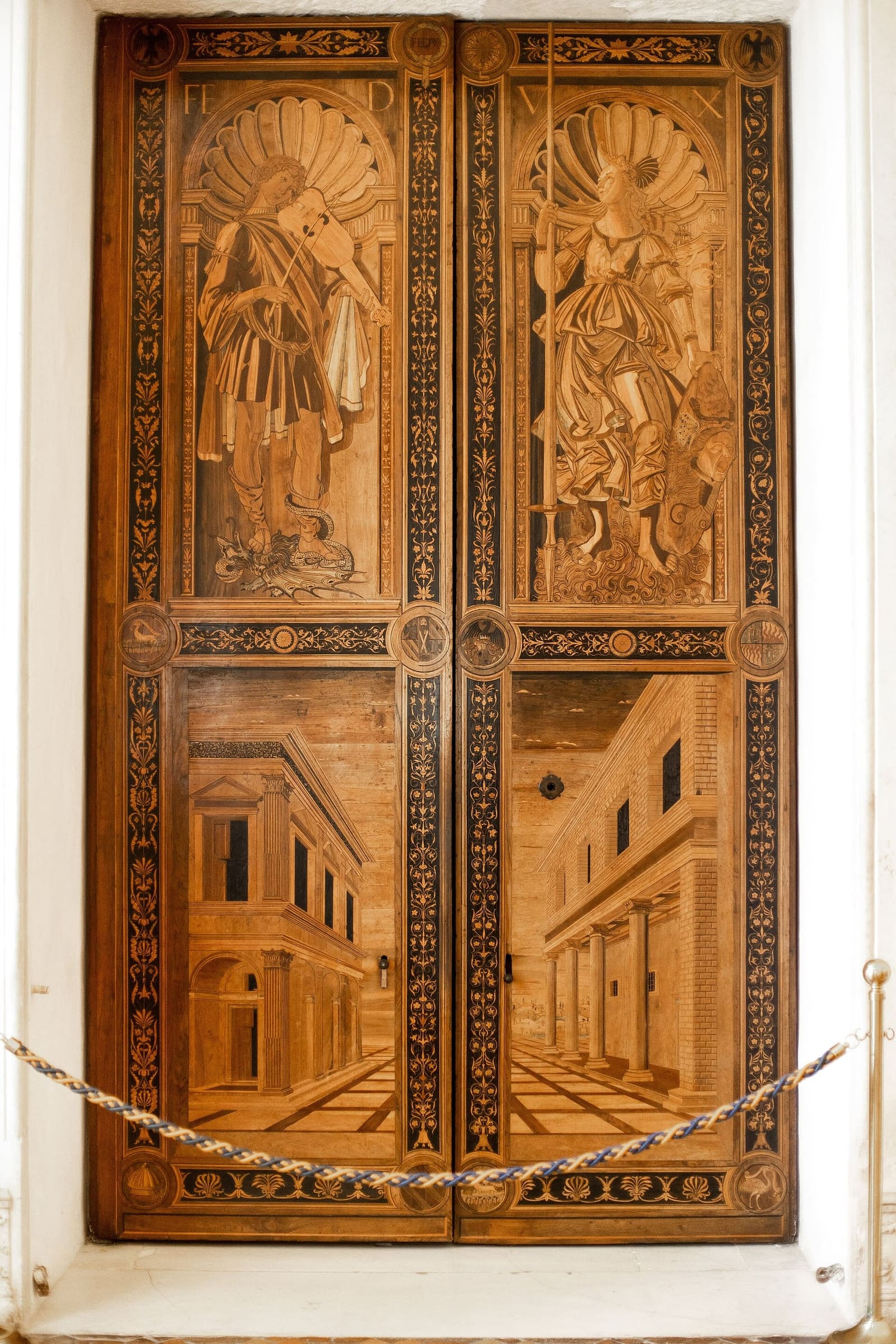 le imposte intarsiate della porta fra la Sala degli Angeli e il Salone del Trono, con le figure in alto e le architetture in prospettiva in basso