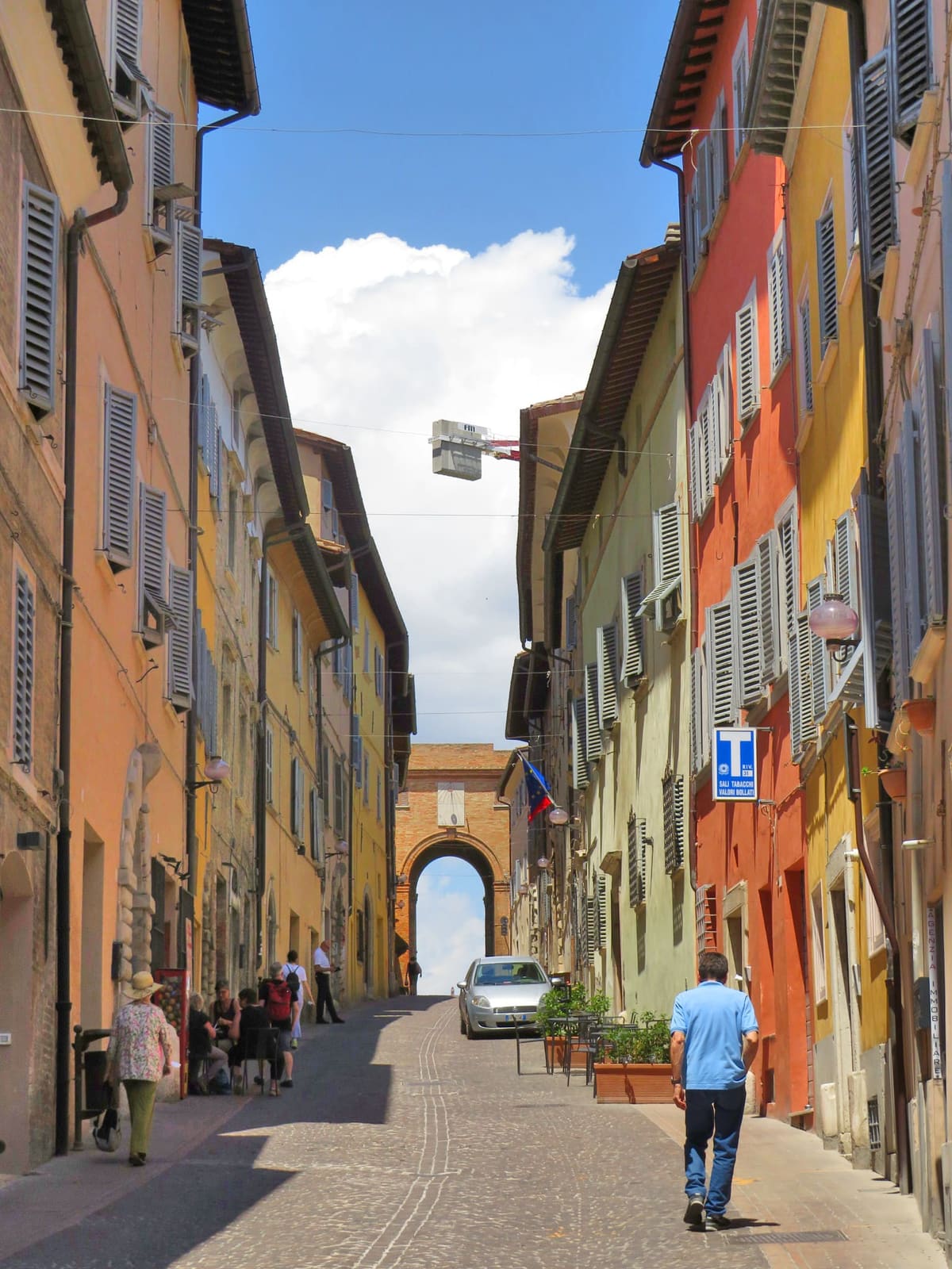 una via in salita fra le case colorate, chiusa in cima da un arco di mattoni con la meridiana