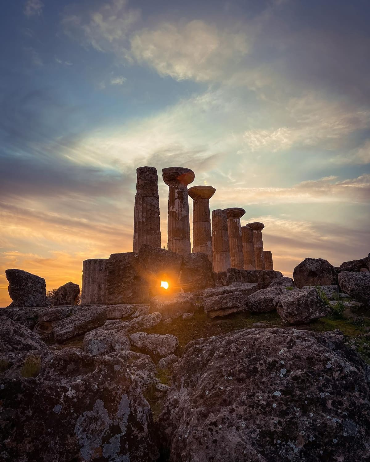 il sole che tramonta fra i blocchi caduti del tempio di Ercole, sotto le colonne rimaste in piedi